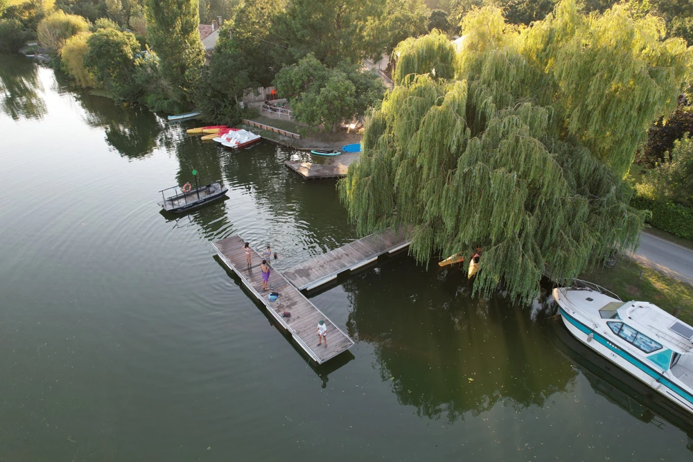 Vue aérienne du ponton du camping Ô P’tit Marais sur la Sèvre Niortaise avec des baigneurs et des canoës.